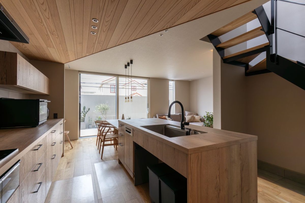 Wood-finished island kitchen with dining area and open stairs